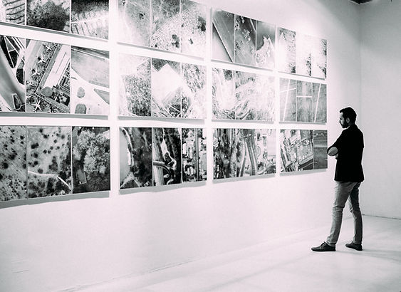 Man admiring photography prints on a wall with his arms folded