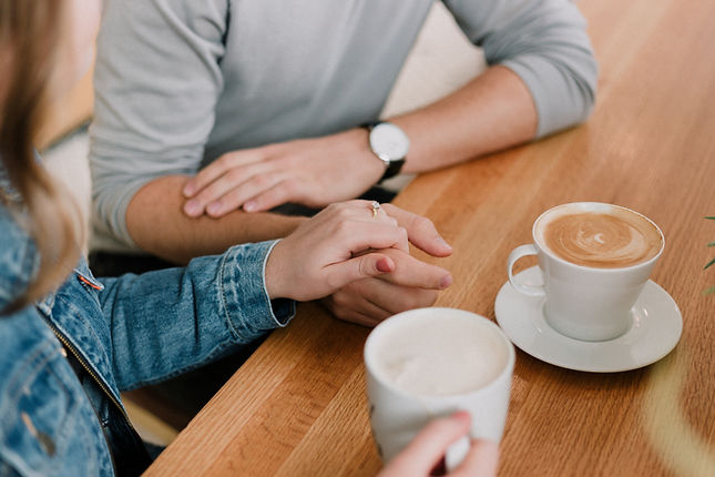A couple hold hands over coffee