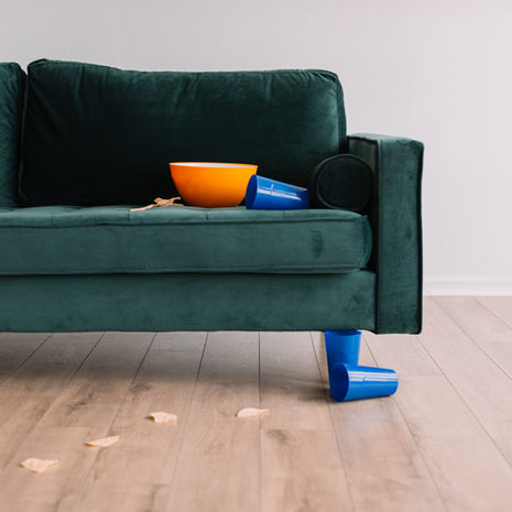 Green sofa on wooden floor in a vacation rental house with a yellow bowl, blue cups, and scattered snacks. 