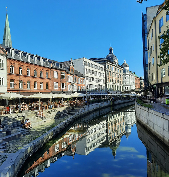 Scene from Aarhus centre, river runs through town with cafees and outdoor seating along the water front. Image by Ioana Grancea