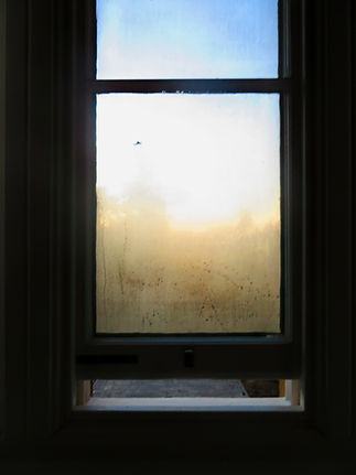 A window with a misty, frosted pane filters soft sunlight