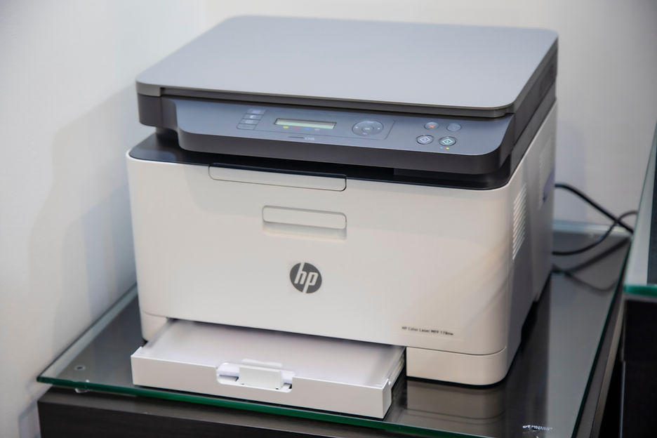A white HP office photocopier and printer standing on a desk