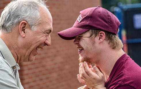 An older man facing a young person smiling and laughing