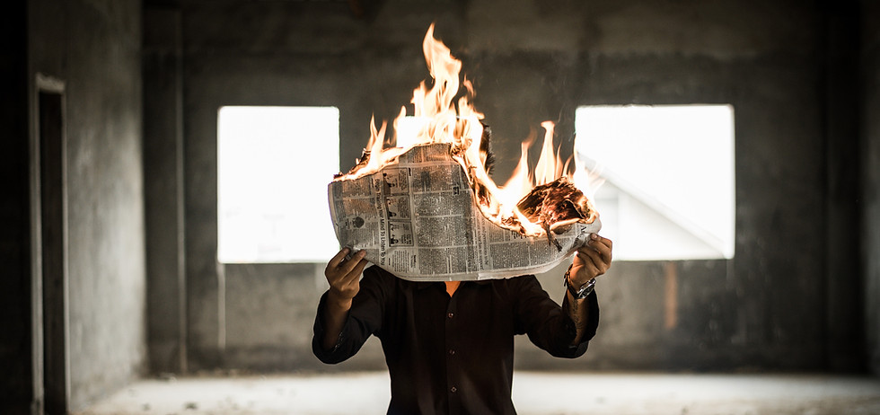 A man holding a burning newspaper