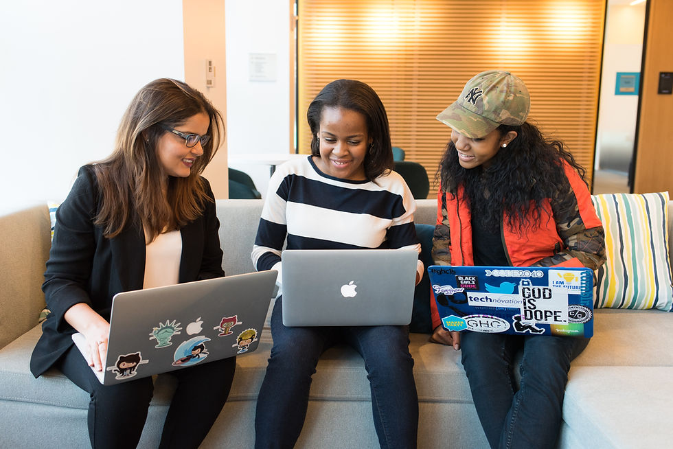 Three woman sitting together with their laptops discussing their work