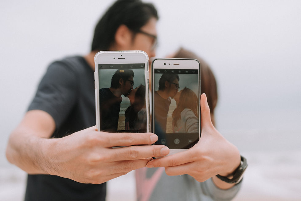 Two people hold up smartphones showing a couple kissing in a selfie, with HDR visible on the camera screens against a soft white background