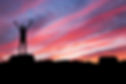 Silhouette of man raising arms with sunset behind