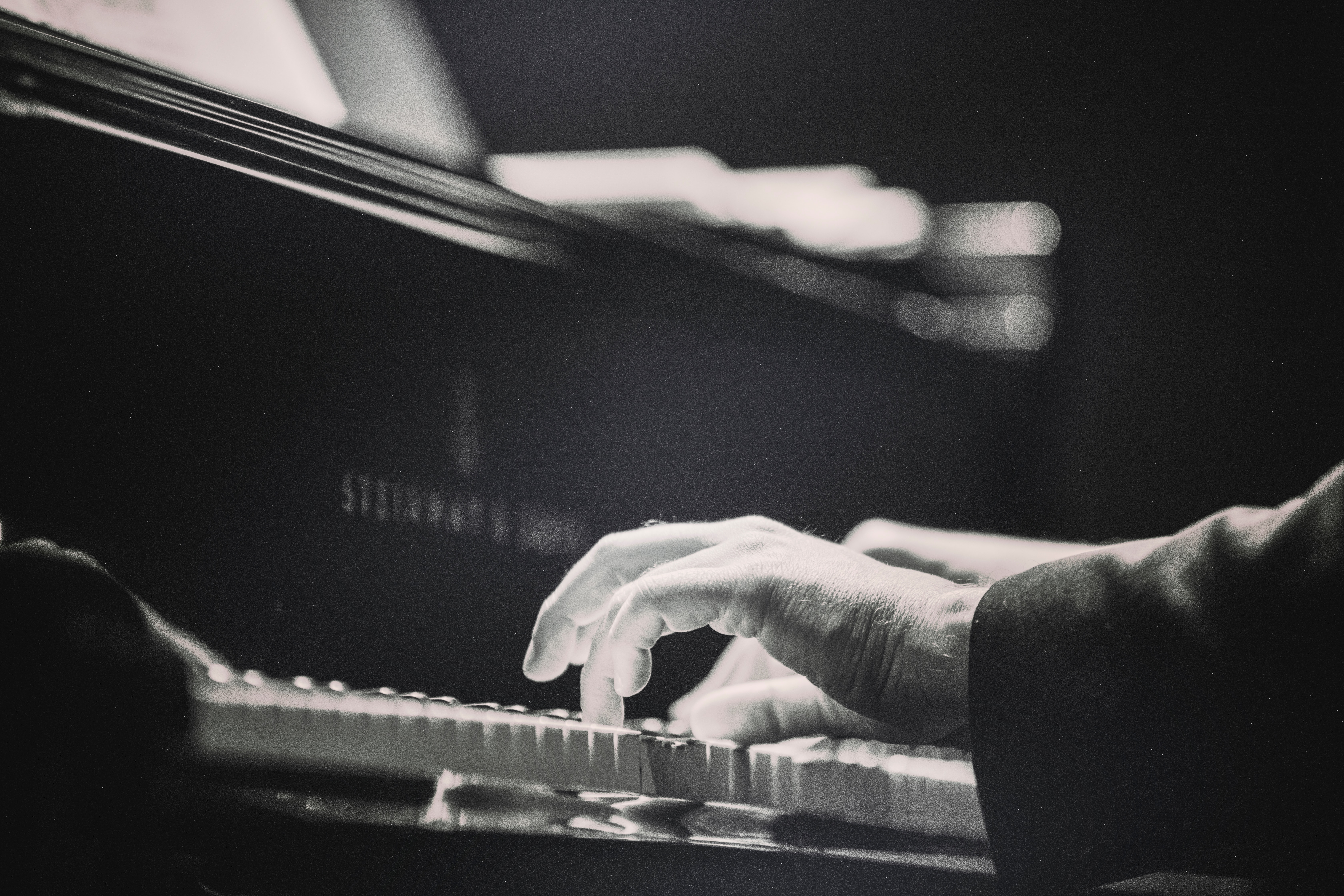black and white image of hands on a piano keyboard, in profile