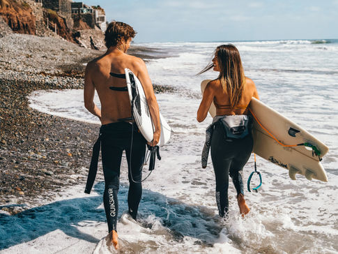 Two surfers carry their surf boards down the shore of a beach in Baja, California.