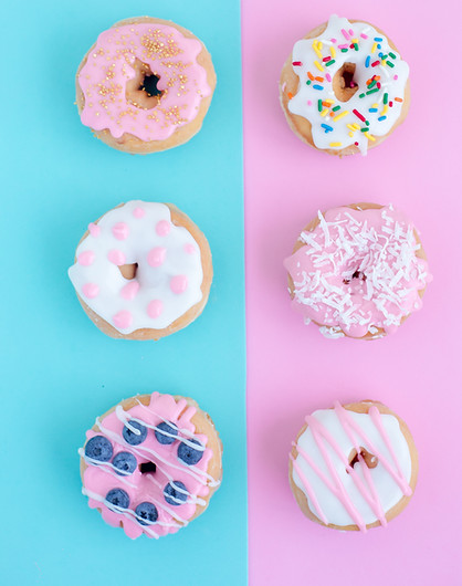 Frosted doughnuts in two lines sit in two rows. The background of one row is blue and the other is pink