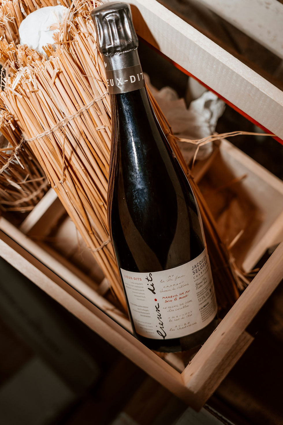 Vintage champagne bottle in a straw-lined wooden crate