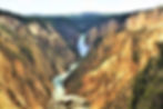 waterfall and gushing river cutting through a canyon of yellow rock