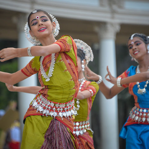 Indian women dressed in vibrant traditional clothing performing a cultural dance outdoors, capturing the energy and heritage of India’s wellness and cultural experiences.