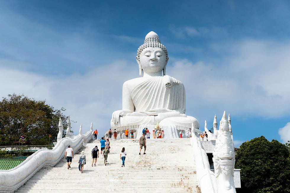 Visitors ascend the grand steps to admire the magnificent white Buddha statue against a serene blue sky.