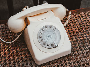 Old rotary phone still on the receiver, white.