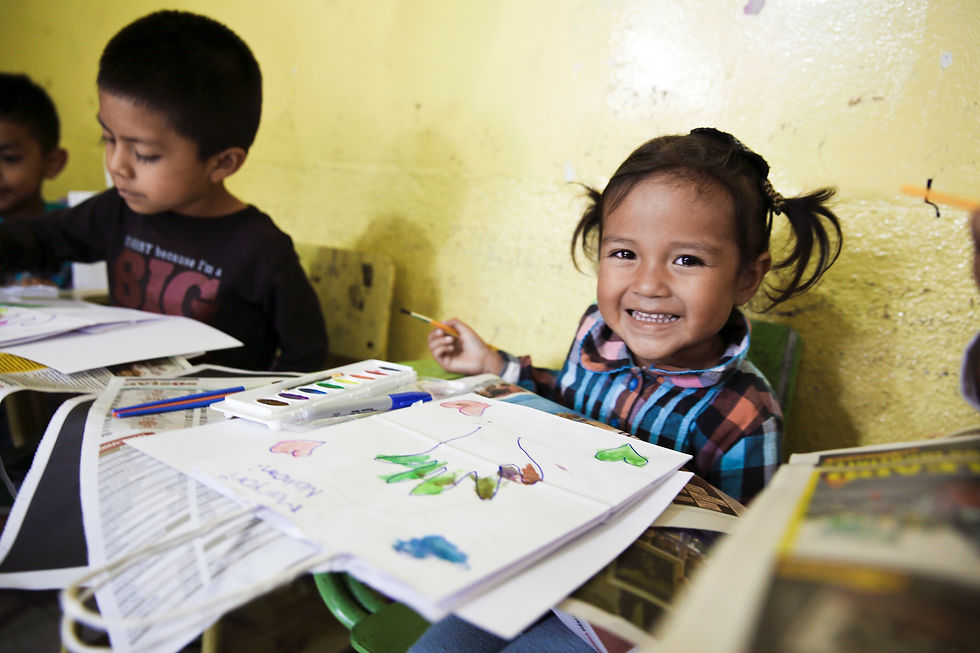 Two preschool kids painting with one of them facing the camera and smiling