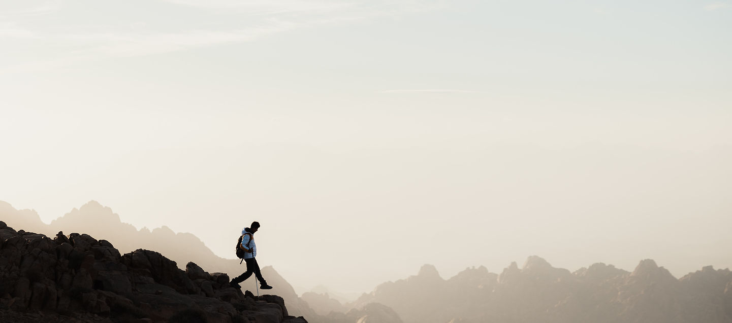 Man taking a step down a mountain range