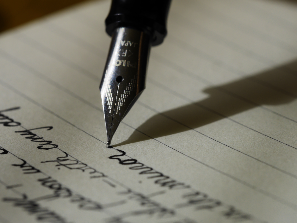 a fountain pen writing on a yellow pad