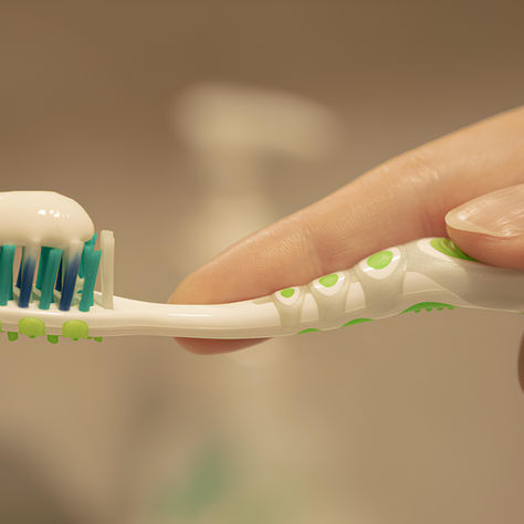 a toothbrush with toothpaste on the bristles being held in the hand