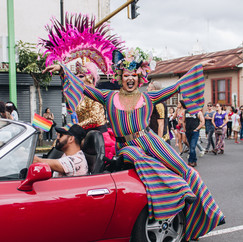 A drag queen sitting on a car in a parade