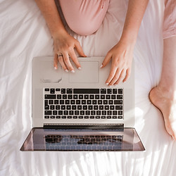 woman operating a personal computer on a bed