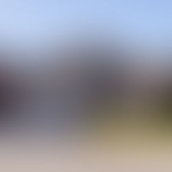 Brick house with double garage, autumn trees, and green shrubs. Clear blue sky and sunlight create a serene suburban atmosphere. Address reads 502.