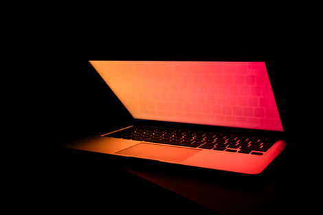Laptop glowing in a dark setting, illustrating cyber security risk, digital systems, and security awareness in the workplace