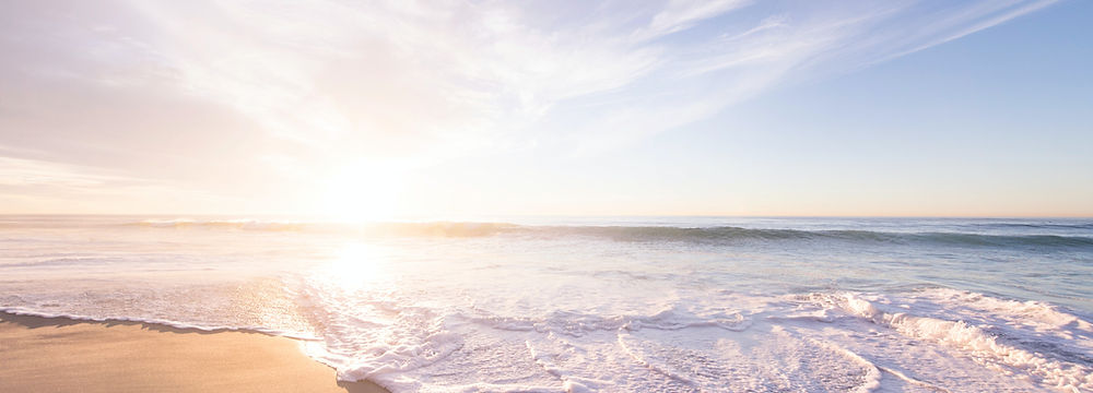 the sun over the ocean with the sand