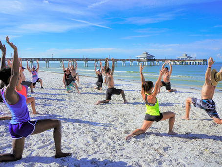 Group practicing yoga by the beach