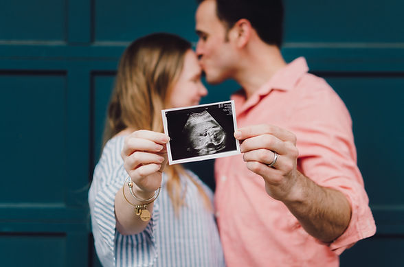 A couple holds up a sonogram photo to announce their pregnancy