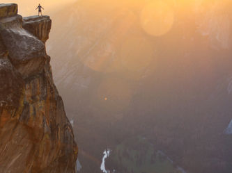A man standing on the edge of a cliff, contemplating the horizon and pondering life's possibilities.