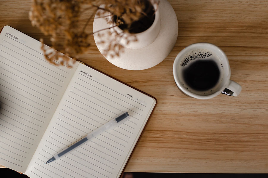 Notebook, pen, and coffee on a wooden desk