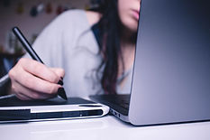 Woman using computer and writing notes