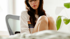 A woman in her 40s sitting quietly in soft natural light with a thoughtful expression, representing the experience of perimenopause heavy periods and the hormonal changes of the menopausal transition from Vibrance Way