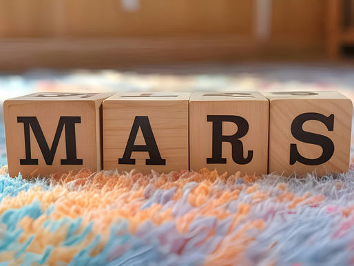 Wooden blocks spell "MARS" on a fluffy, multicolored rug. Warm lighting creates a cozy atmosphere.