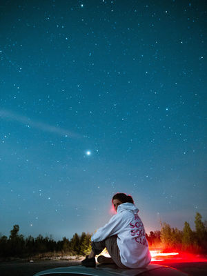 A woman sits and looks at the brightest star in the night sky