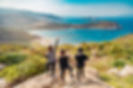 Group of 3 friends looking at the sea on top of a mountain