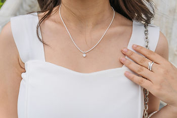 Woman in white dress wearing a silver necklace with a gemstone pendant. high-contrast styling paired with Shokoro Handmade Howlite jewelry.
