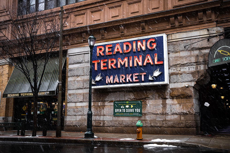 Snowy street outside Reading Terminal Market with neon sign, wet sidewalk, and a fire hydrant in front.