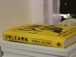 Yellow book kept on a rack with the title "Unlearn"