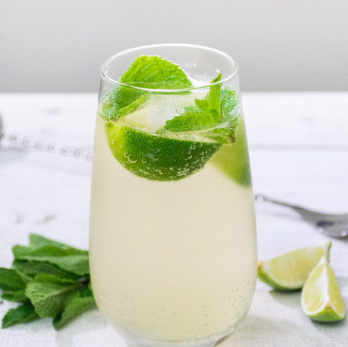 Margarita cocktail in a glass with lime wedges and mint leaves