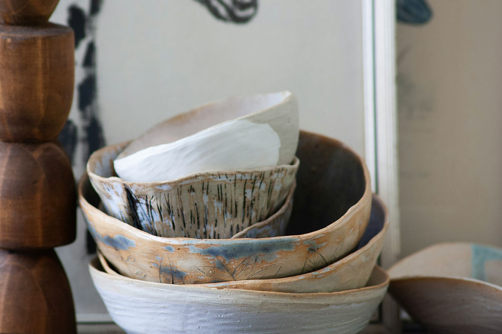 Stacked ceramic bowls with earthy tones and abstract patterns, set against a wooden stand and neutral background. Calm and artistic mood.