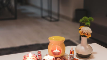 A cozy living room with soy candles on a table—one lit, one unlit. Alt Text: Soy candles lit in a cozy eco-friendly home setting.