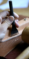 Des artisans du cuir travaillant avec soin pour créer des sacs et des ceintures de qualité dans leur atelier d'Arbois.