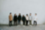 Young adults standing by a white wall