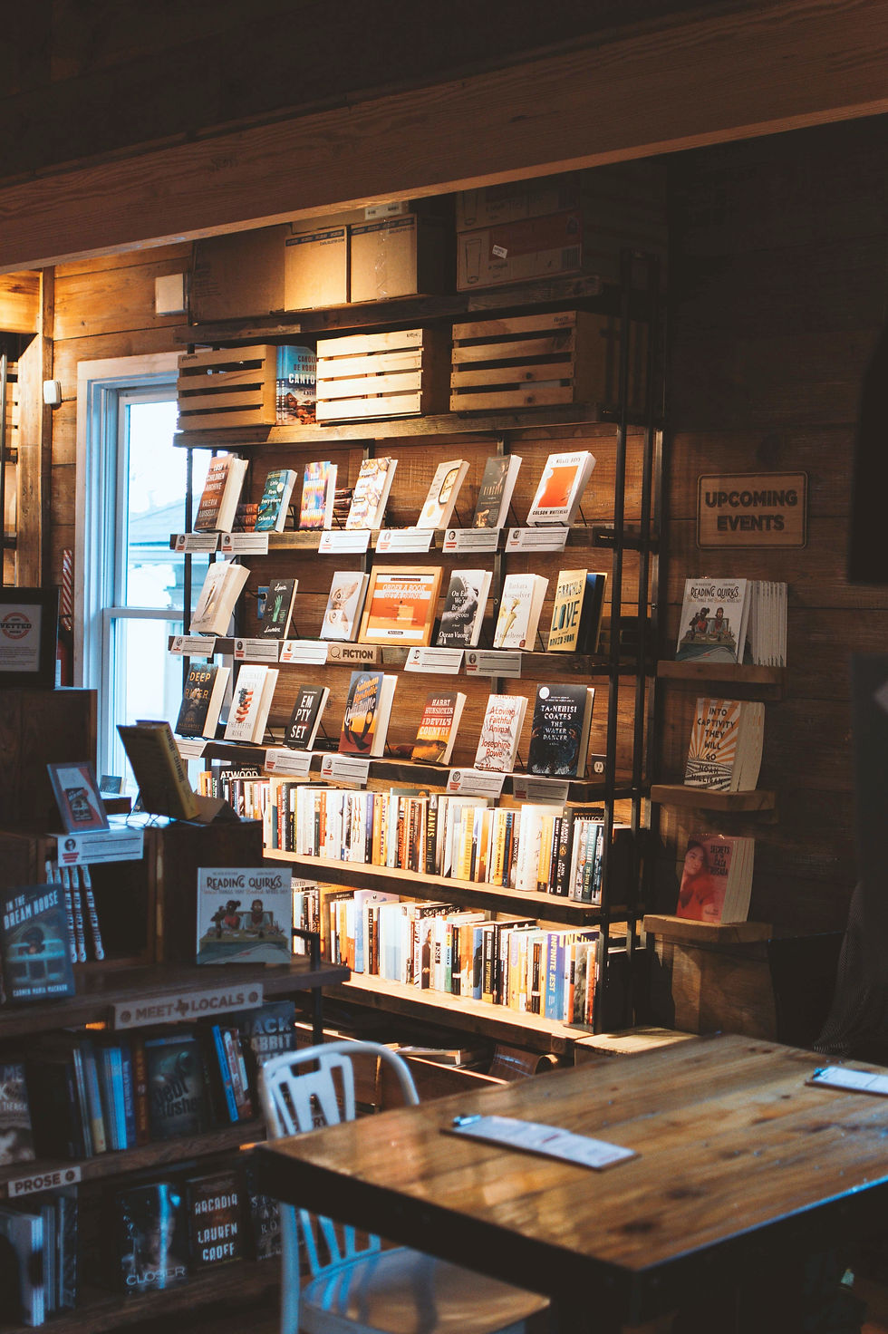 Book store with multiple books on the shelves, sun shining through the window to the left