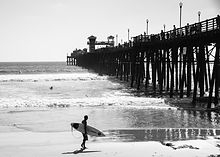 Man with surfboard walking at the beach - Image by Chris Grafton