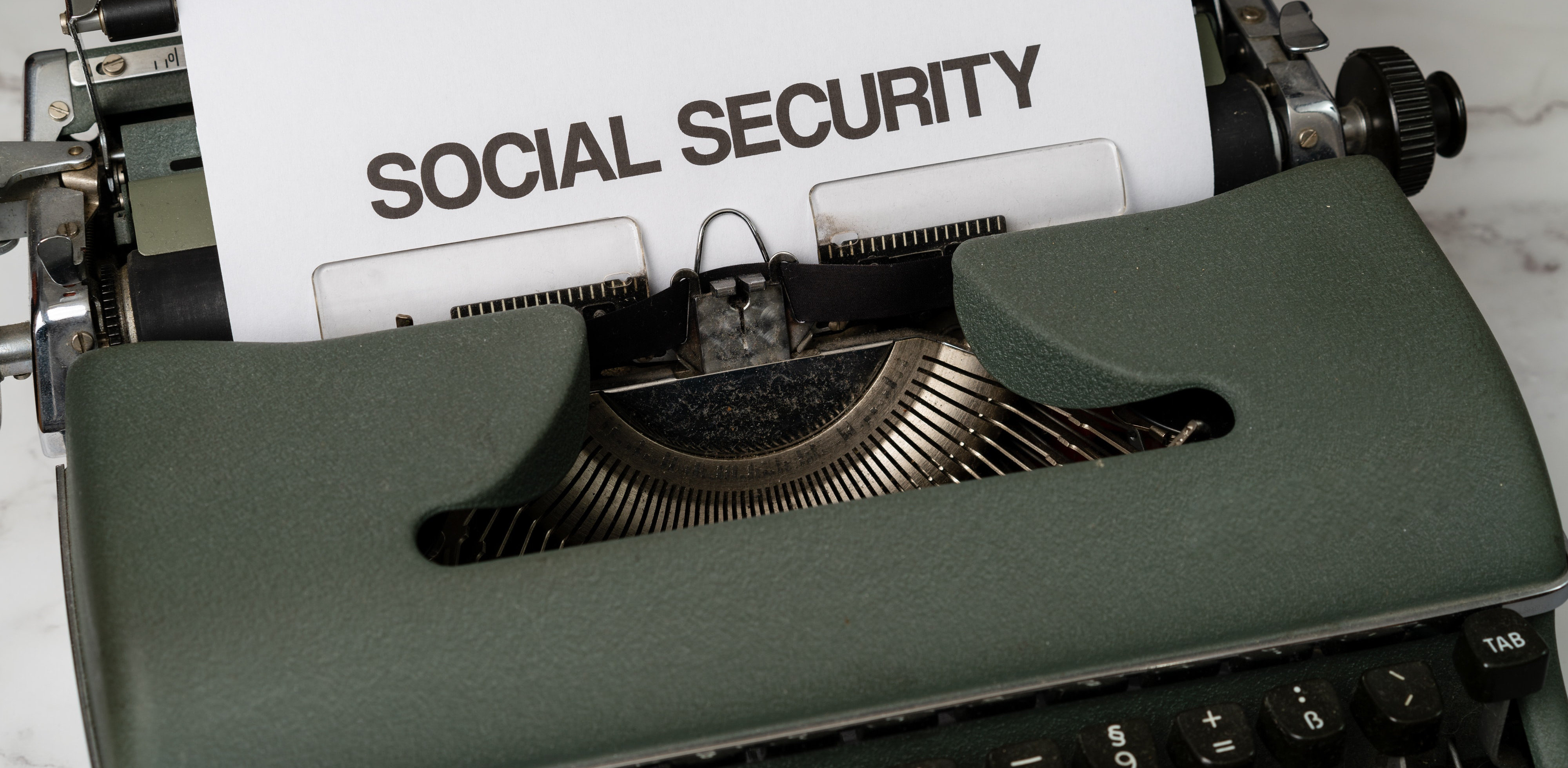 Vintage typewriter with paper reading SOCIAL SECURITY, on a marble surface, evoking a formal, bureaucratic mood.