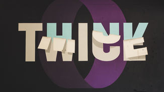 The word "THINK" is painted on a black wall, with letters in white and light blue overlying a purple circle. Some letters appear as if peeling.