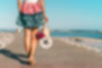 woman walking on beach with purse